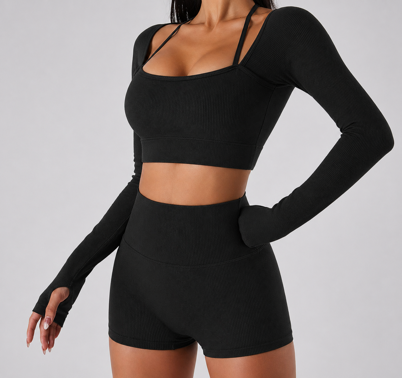 Black athletic outfit with long-sleeve top and shorts on a gray background