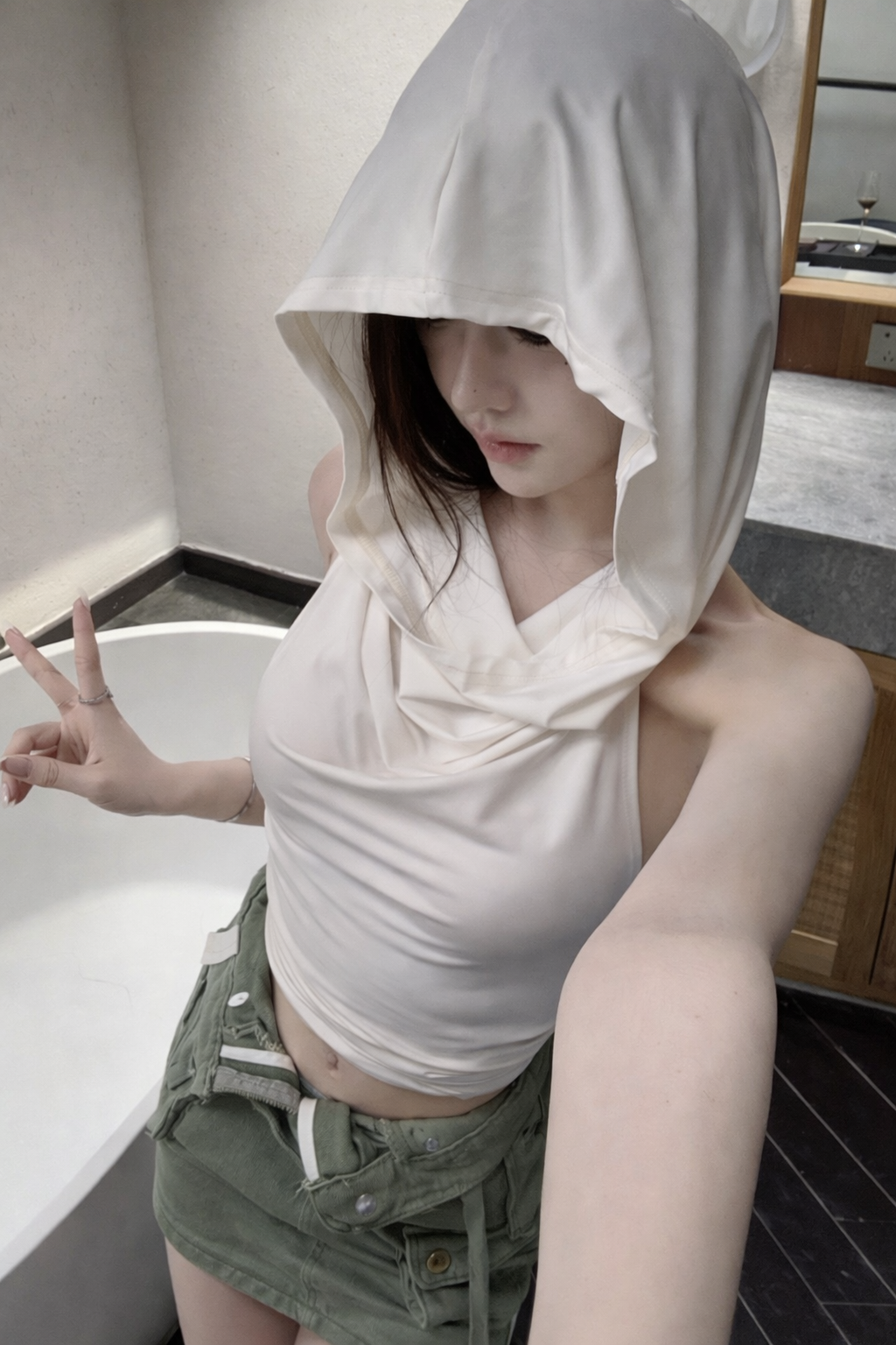 Person wearing a white hoodie and green shorts in a bathroom setting