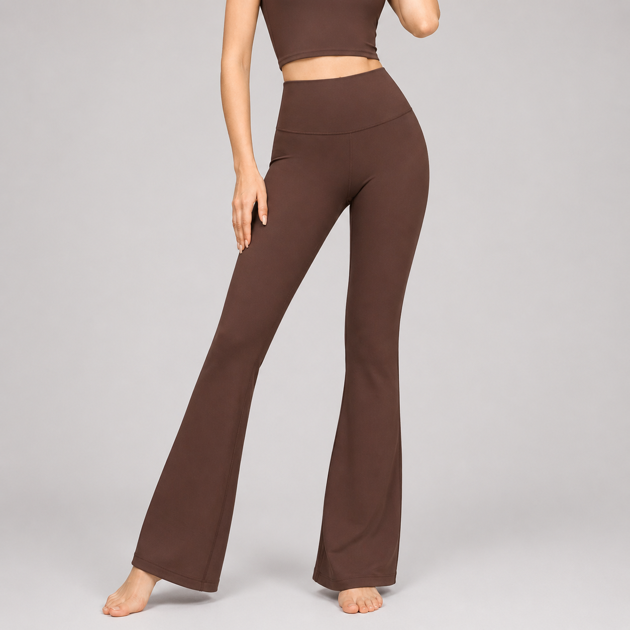 Brown flared pants worn by a person on a gray background