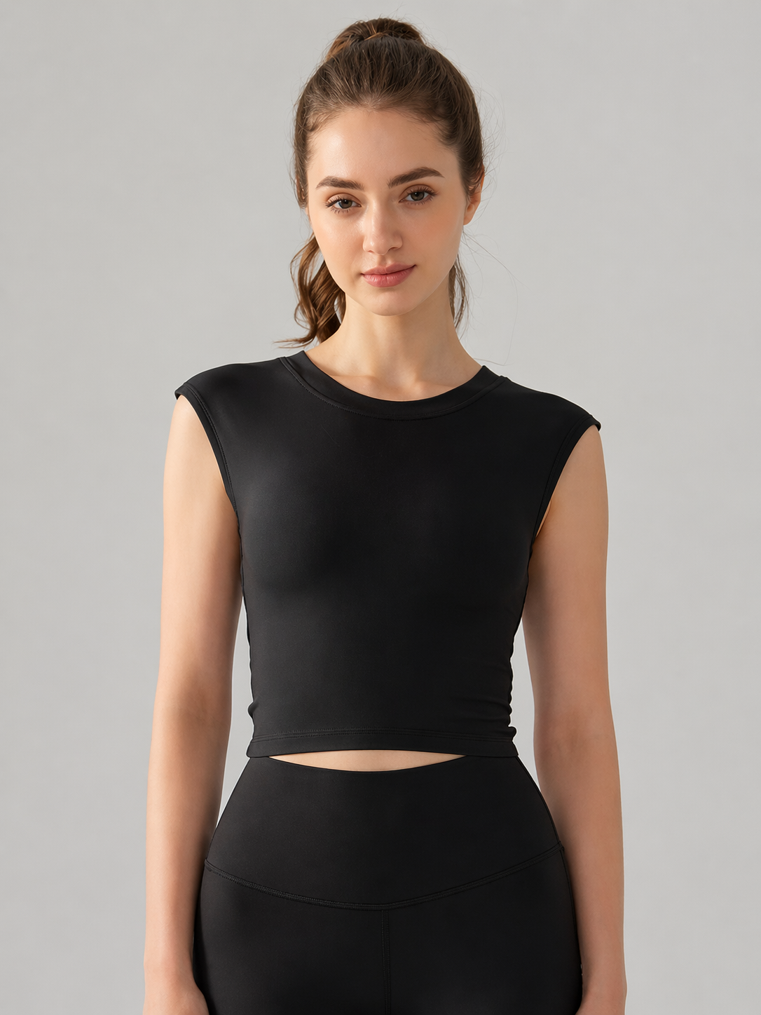 Woman wearing a black sleeveless top against a gray background
