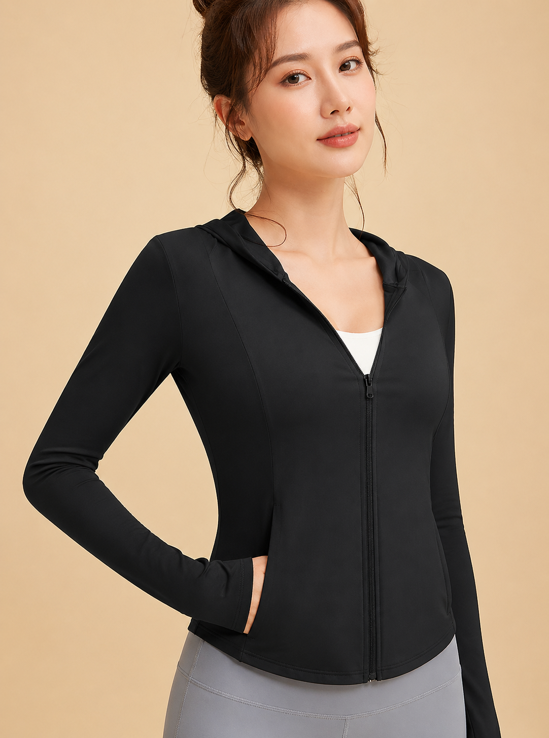 Woman wearing a black zip-up hoodie on a beige background