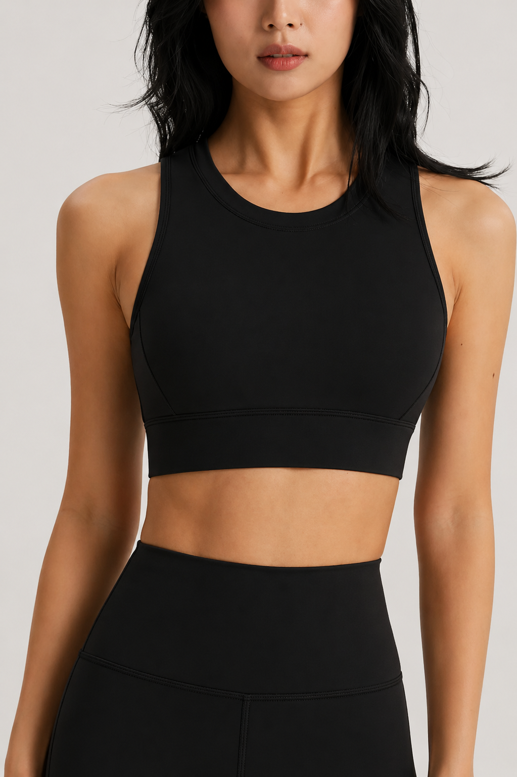 Person wearing a black sports bra and leggings on a light gray background