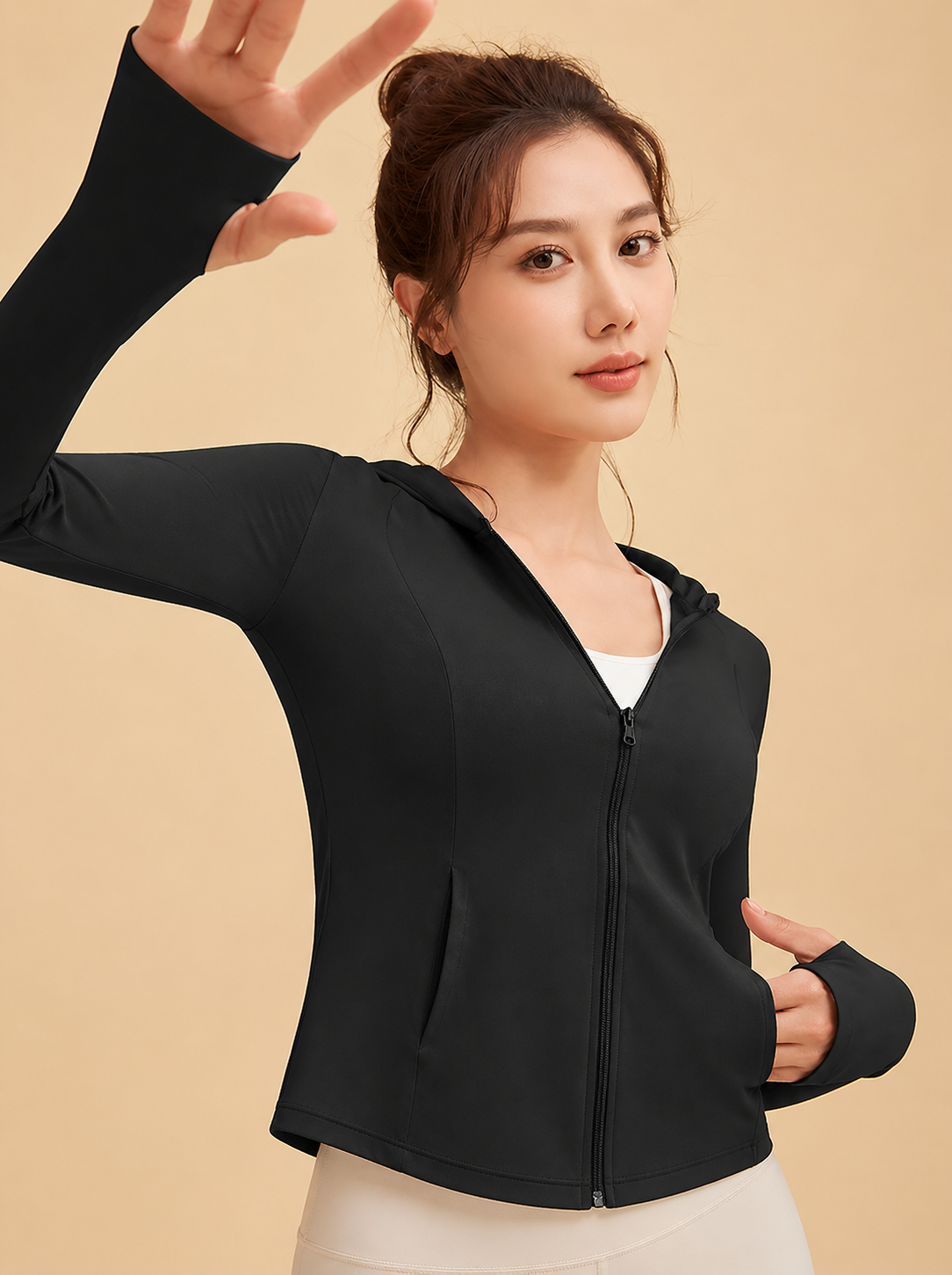 Woman wearing a black zip-up hoodie against a beige background
