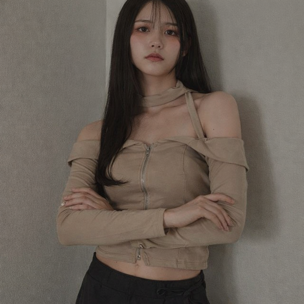 Woman wearing a beige off-shoulder top against a gray wall