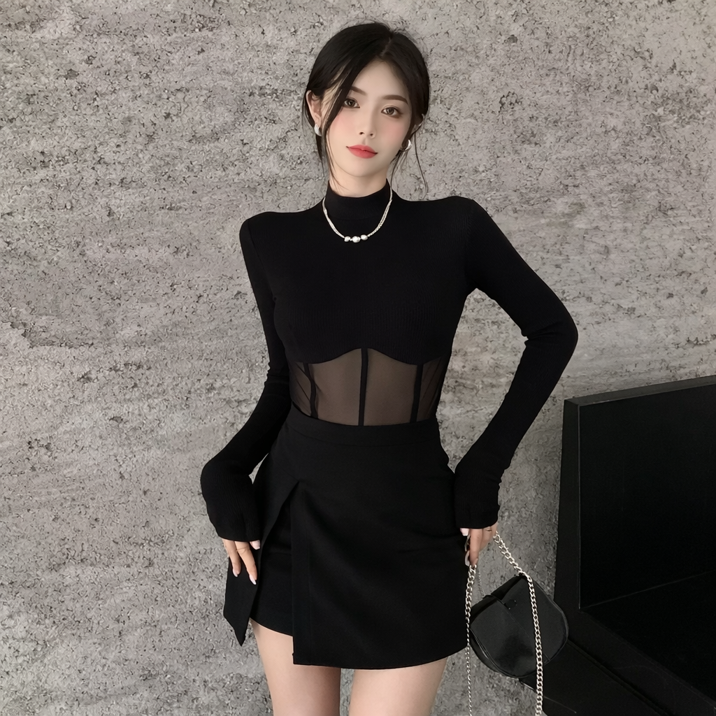 Woman wearing a black outfit with sheer panels against a textured wall.