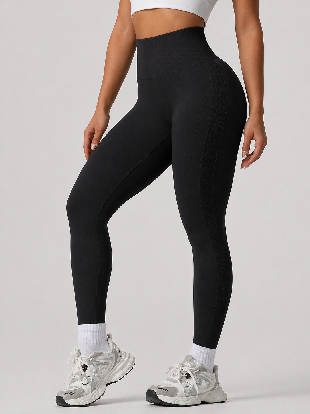 Person wearing black leggings and white sneakers on a gray background