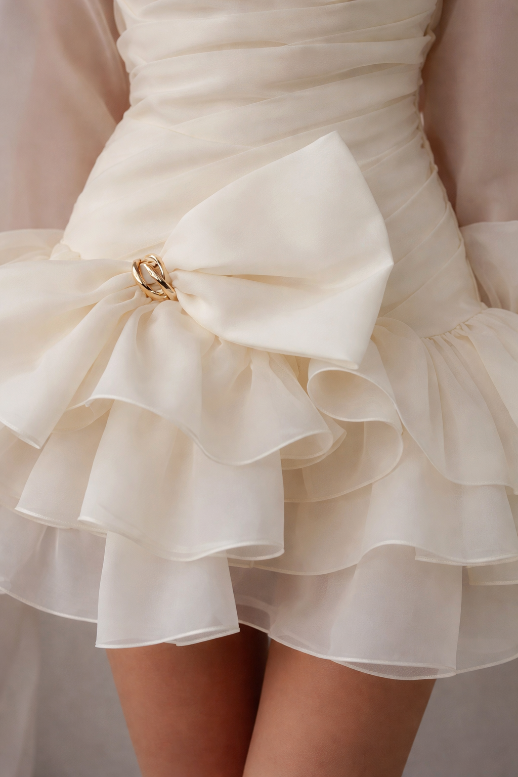 Close-up of a white dress with a large bow detail on a neutral background