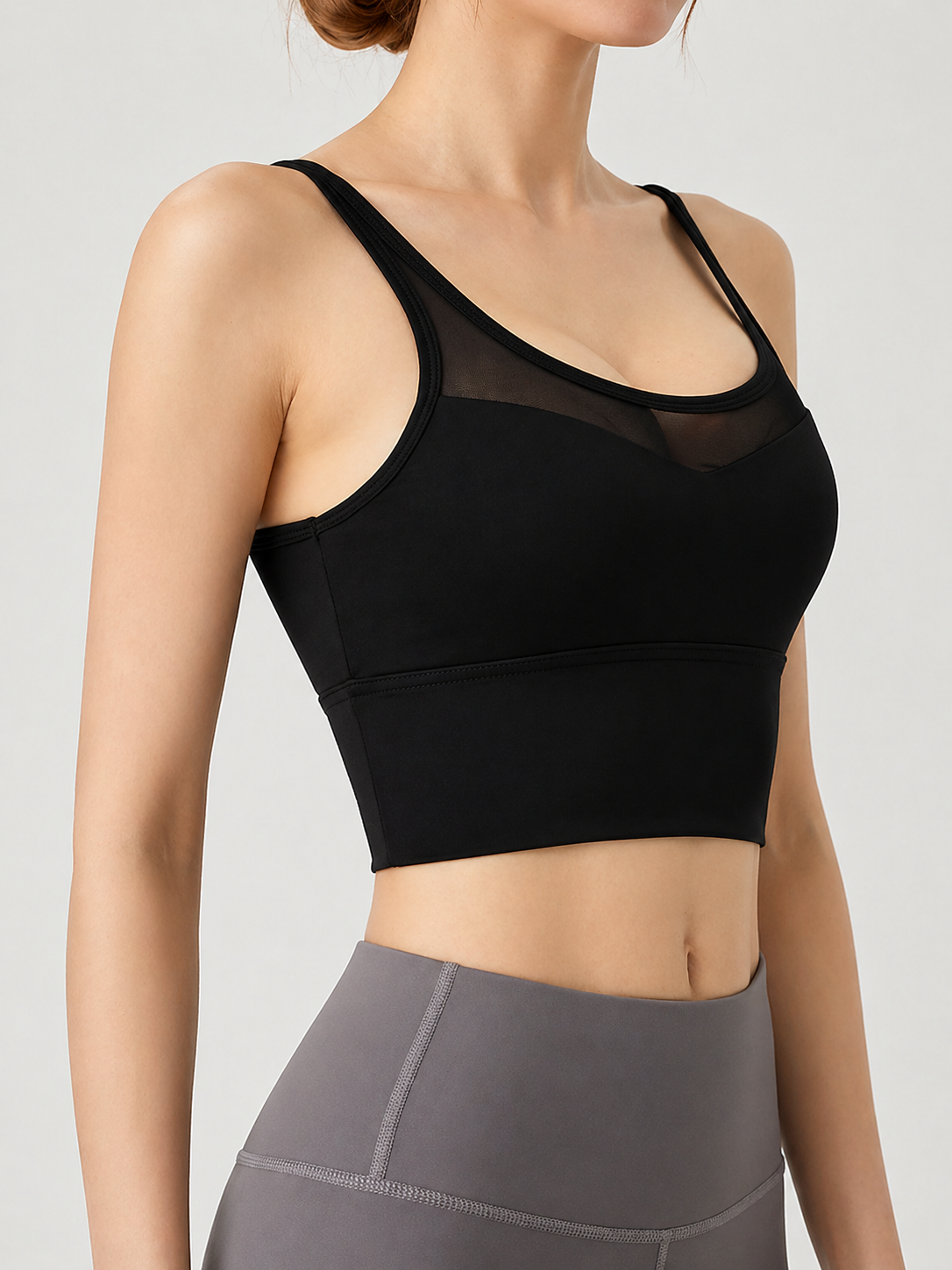 Person wearing a black sports bra and gray leggings on a light gray background