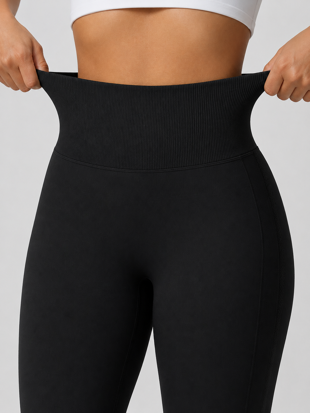 Person wearing black leggings with a plain background