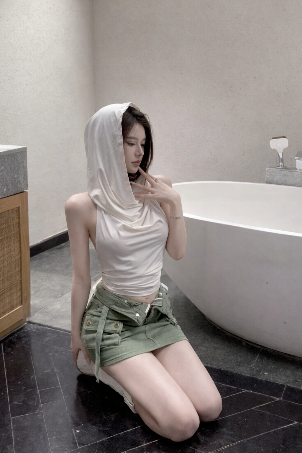 Woman sitting on the floor in a bathroom with a towel over her head