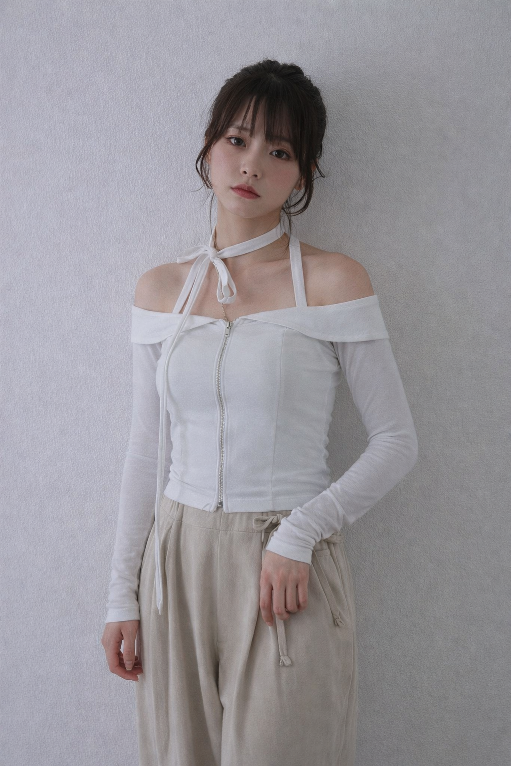 Woman wearing a white off-shoulder top and beige pants against a plain background