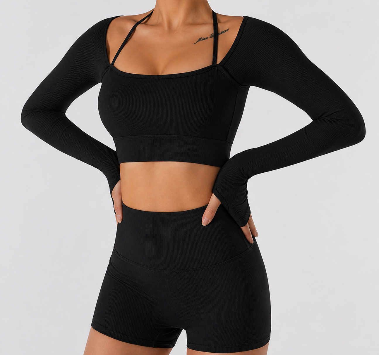 Person wearing a black long-sleeve crop top and shorts on a light gray background