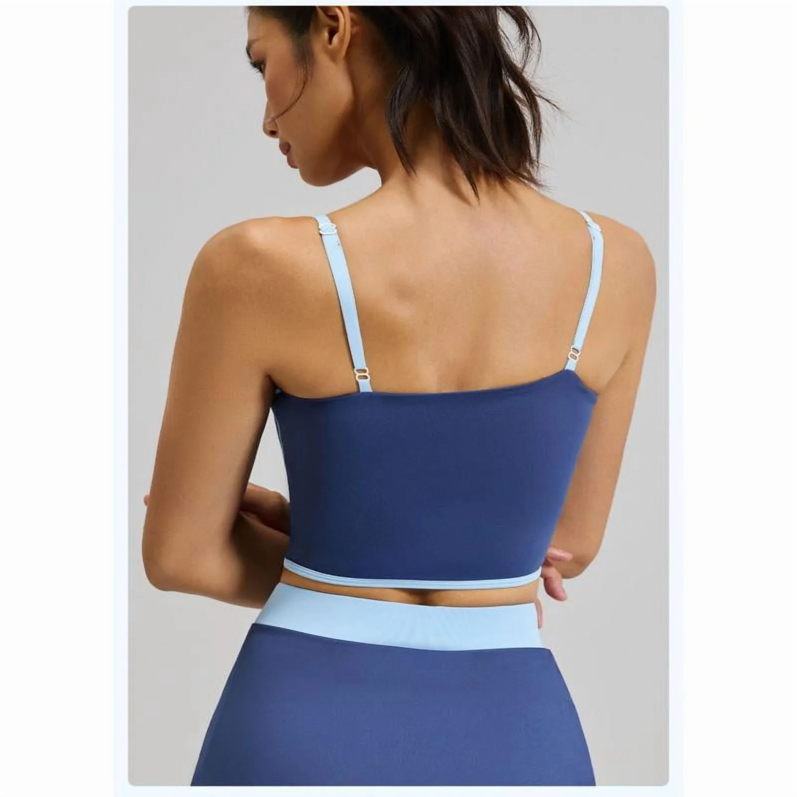 Woman wearing a blue sports bra and leggings set on a plain background