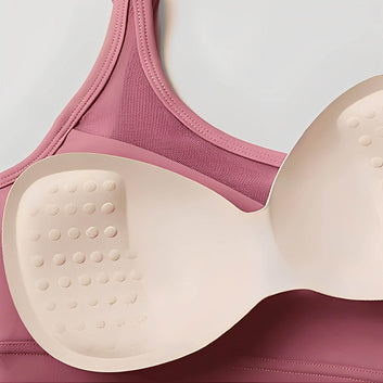 Pink bra with beige silicone gel pads on a light gray background
