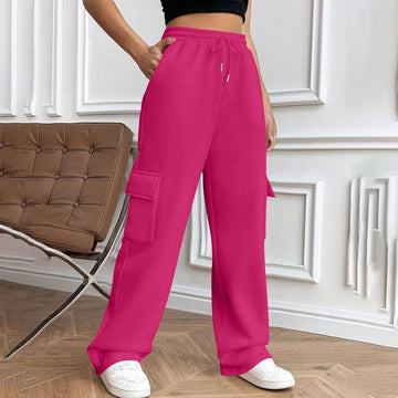 Person wearing bright pink cargo pants in a room with a brown chair and white walls.